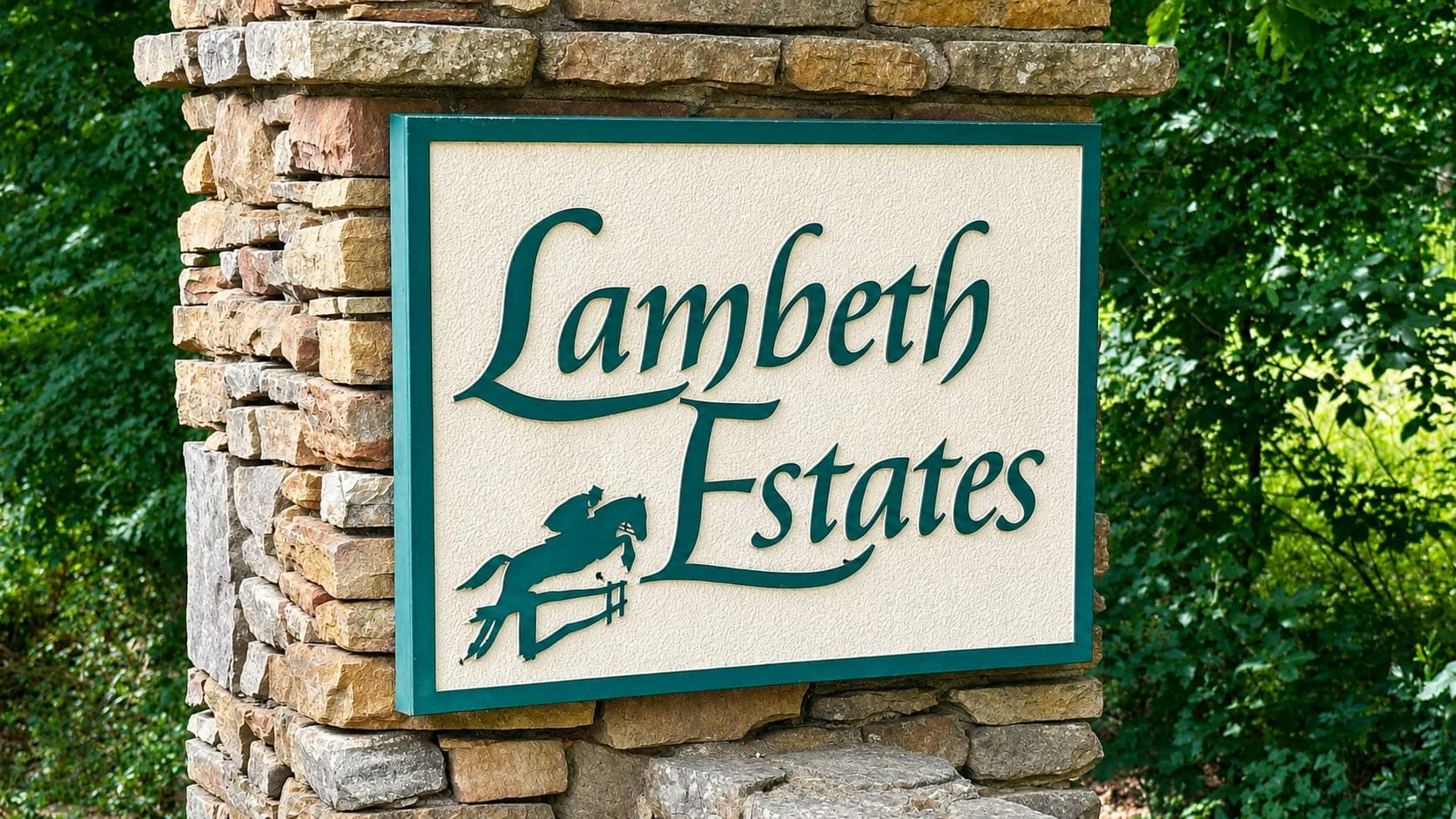 The Lambeth Estates entrance sign, carved with the association's jumping-horse emblem and set into a dry stone wall surrounded by greenery.