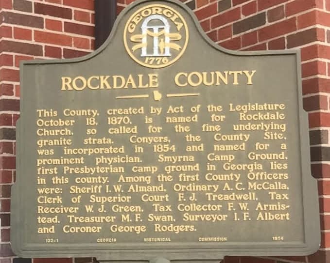 Georgia Historical Commission marker for Rockdale County, mounted on a brick wall in Conyers, recording that the county was created in 1870.